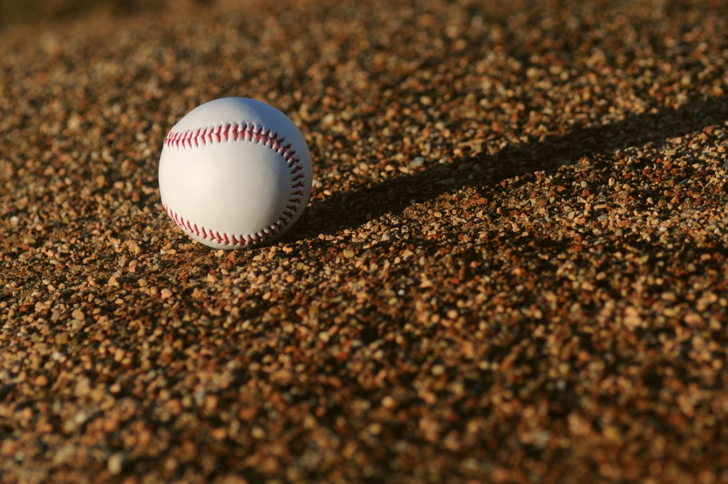 A baseball sitting on dirt.